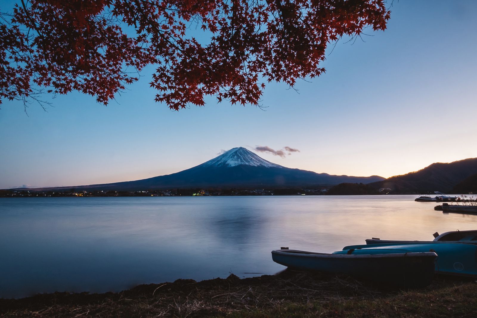Mount Fuji reflected in Lake Kawaguchiko at dusk, framed by autumn maples